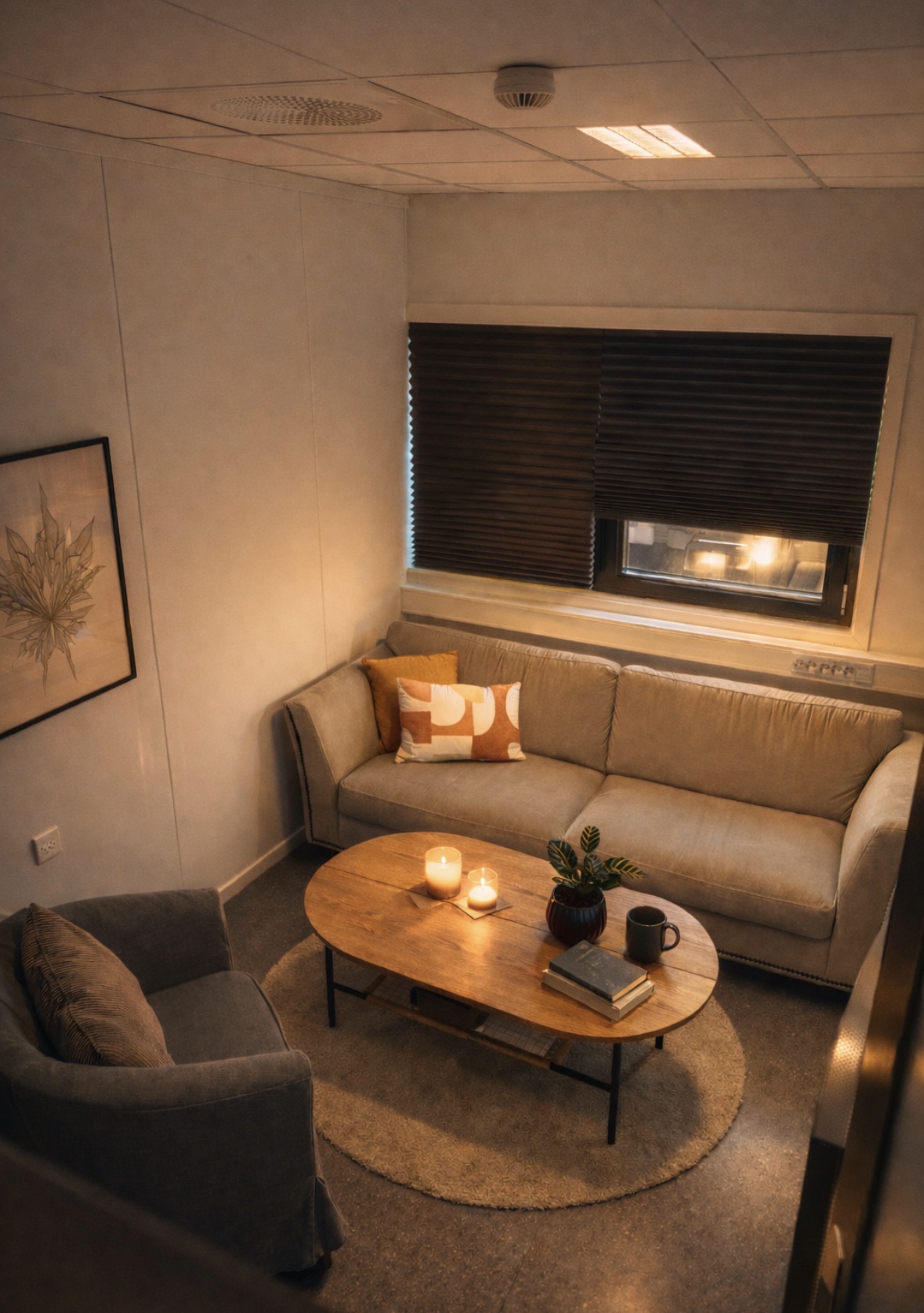 Terapirom hos SansHera Helhetsterapi på Jessheim, en beige sofa og en beige stol, et salongbord dekorert med en plante og et pyntebrett med lys og drikke på, koselig og trygt rom